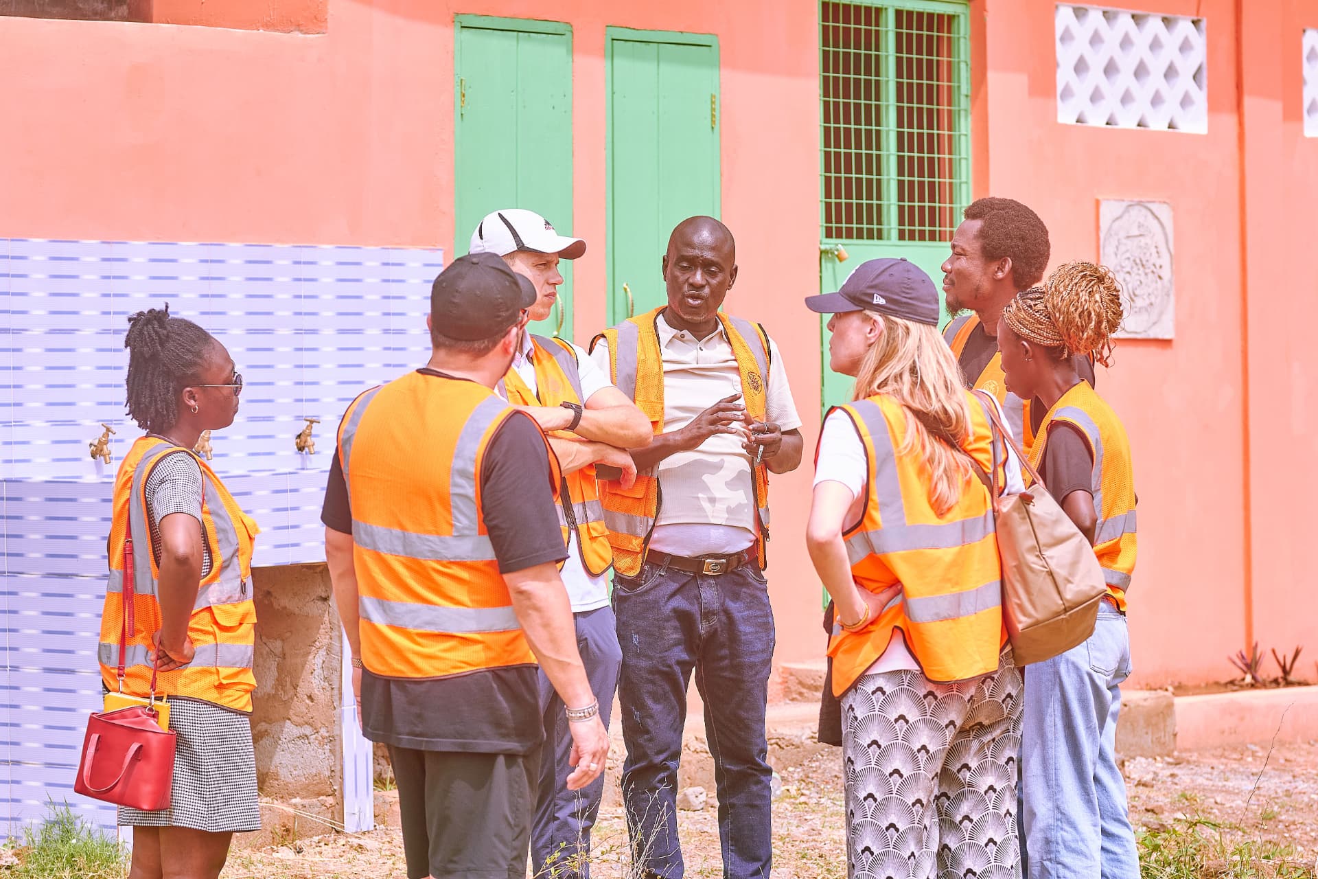 The project team meets outside the new toilet block, next to a tiled handwashing station with taps