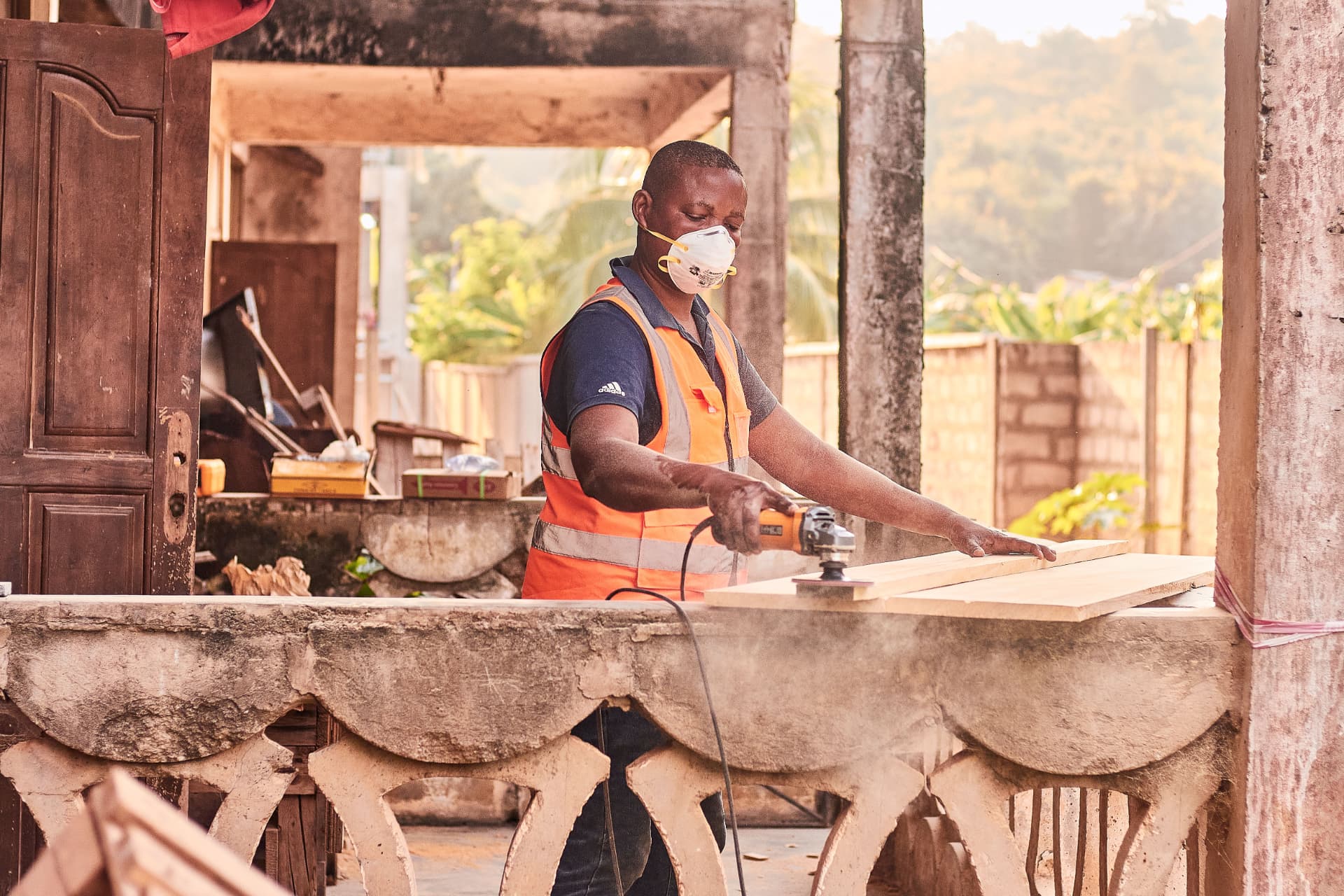 A worker sands a wooden plank with a power tool during the construction of a school facility