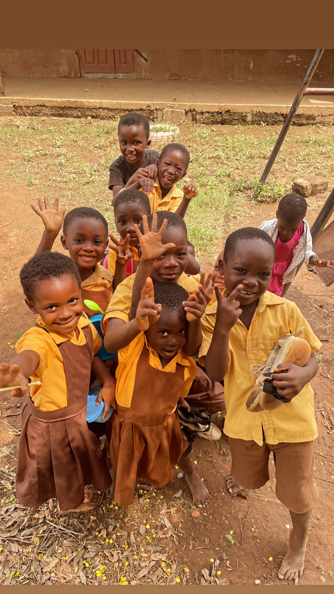 A group of children waving and laughing in front of the camera