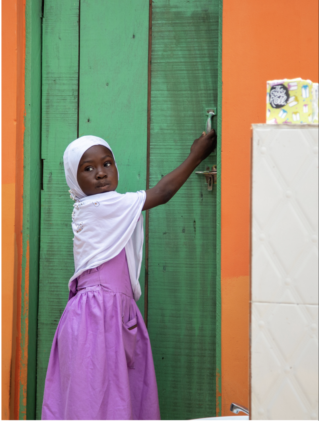 A girl opens the door of a colourful Good Roll school toilet